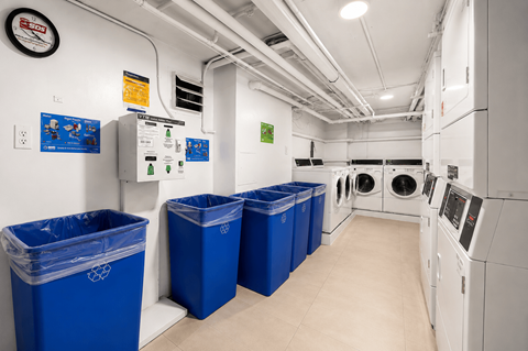 A laundry room with washers and dryers and blue bins.
