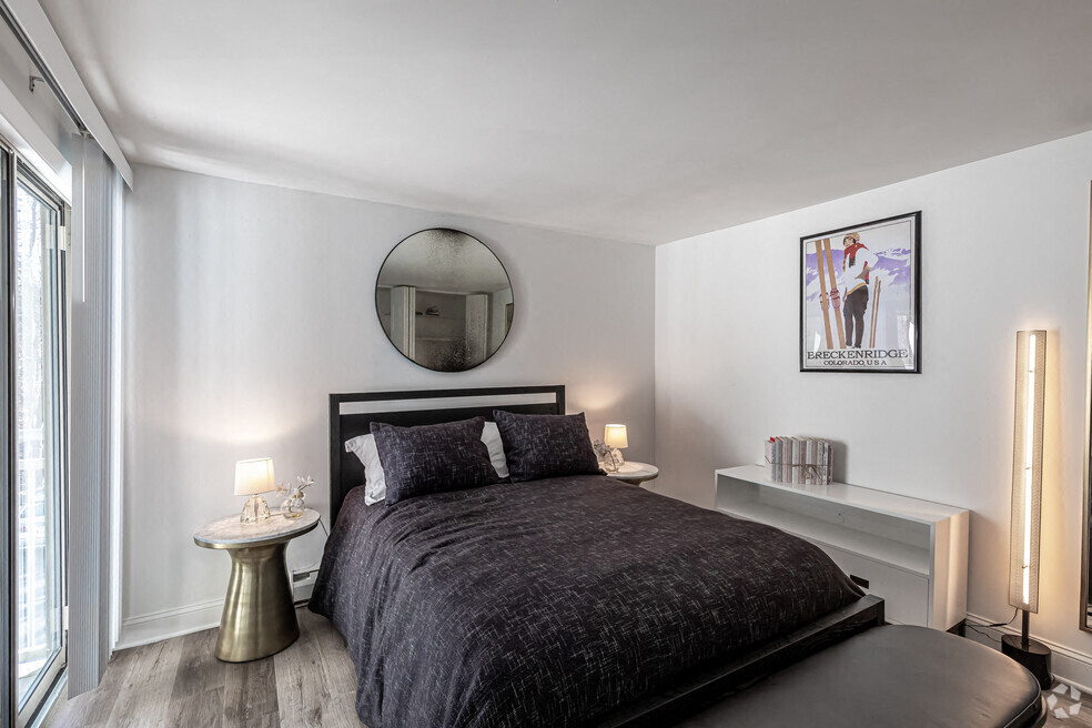 A bedroom with a large bed and a round mirror on the wall.