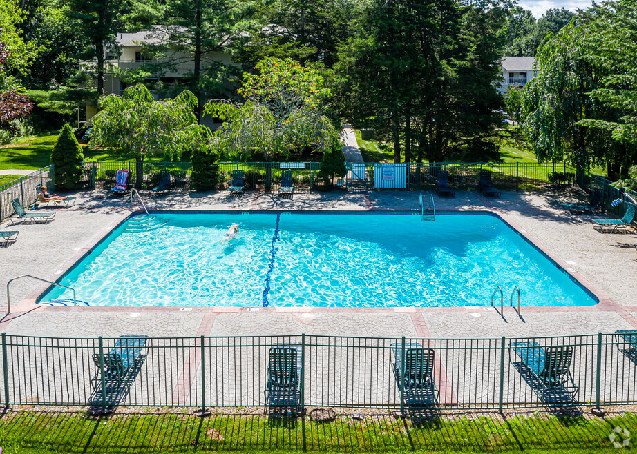 A large swimming pool surrounded by a black fence and lounge chairs.