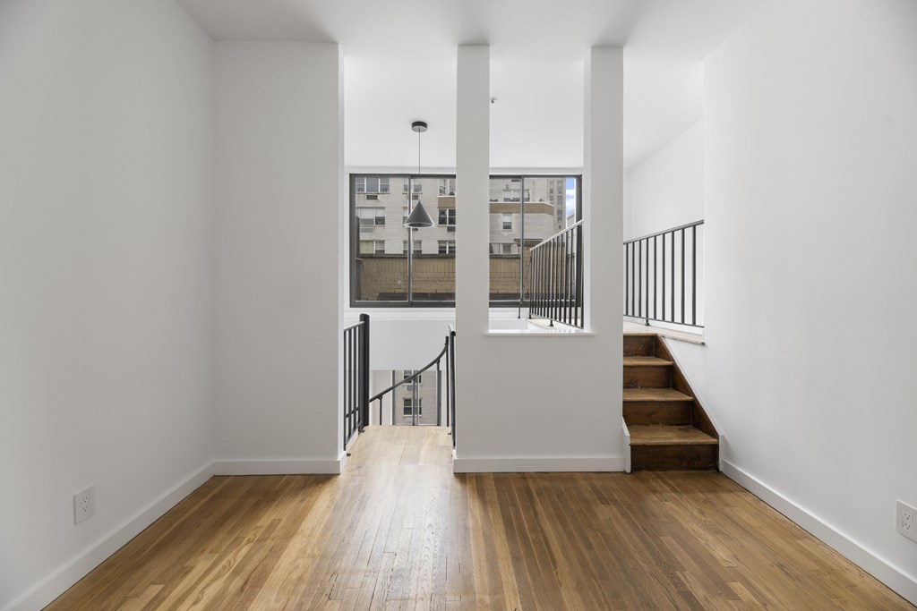 A long hallway with a staircase and a balcony.