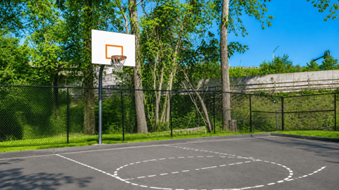 A basketball court with a hoop and a fence.