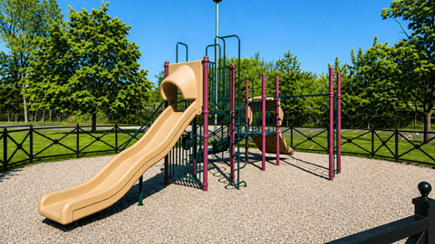 A playground with a yellow slide and a green swing set.