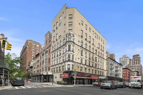 A street view of a city with a large building in the middle and cars on the road.