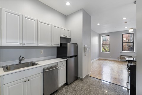 A kitchen with white cabinets and a black refrigerator.