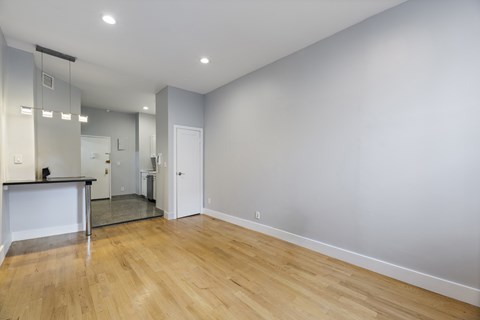 A spacious room with wooden flooring and a large mirror on the wall.