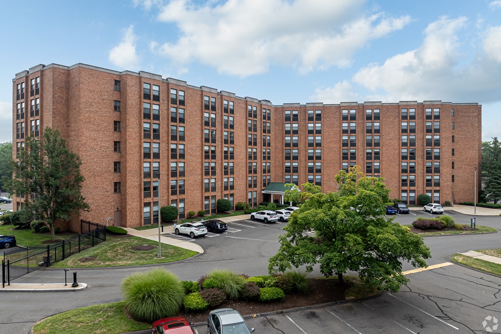 A large red brick building with a parking lot in front.