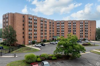 A large red brick building with a parking lot in front.