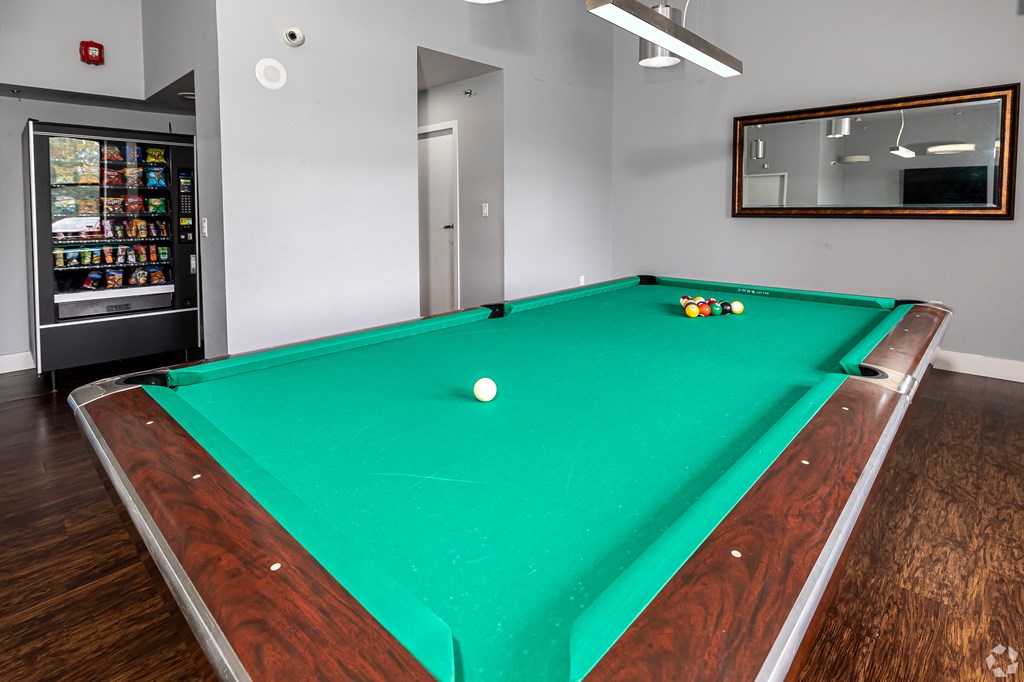A pool table with a green cloth and a white ball in the middle.