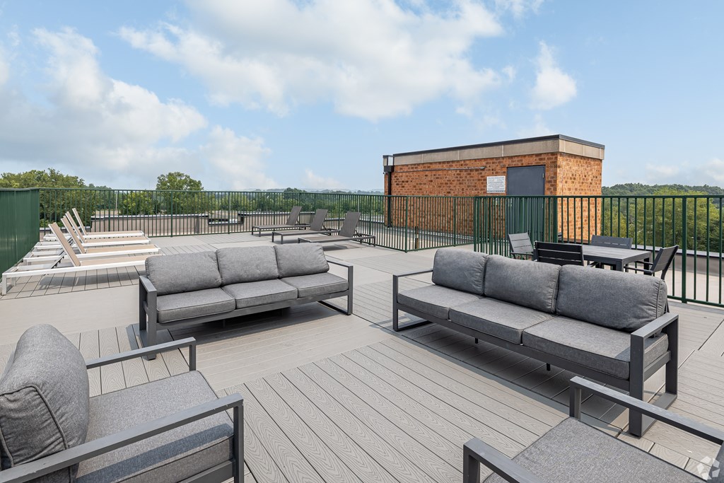 A wooden deck with two grey couches and a black metal fence.
