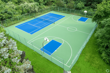 A tennis court surrounded by a fence and trees.