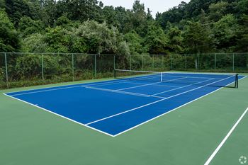 A tennis court surrounded by a green fence.