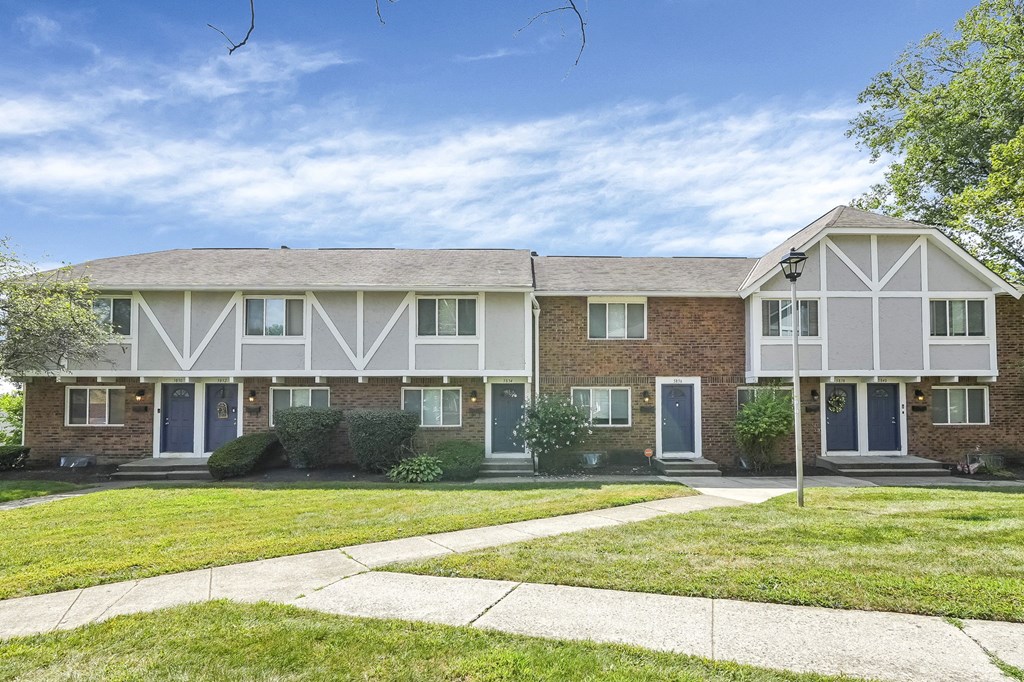 A row of houses with a sidewalk in front.