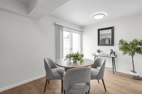 A dining room with a round table and grey chairs.