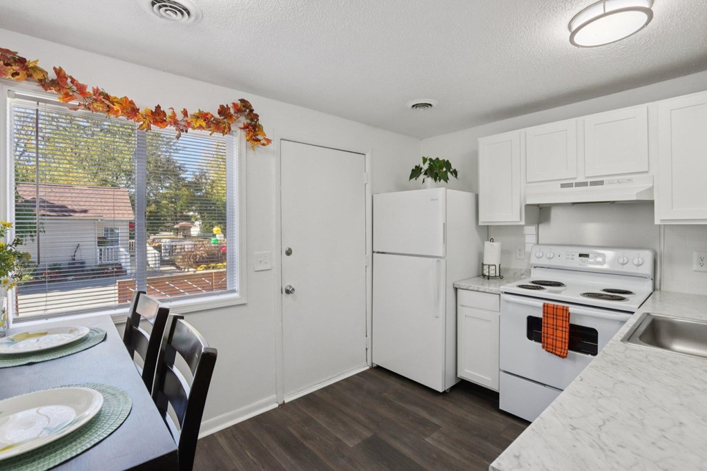 A kitchen with white appliances and a table with plates on it.