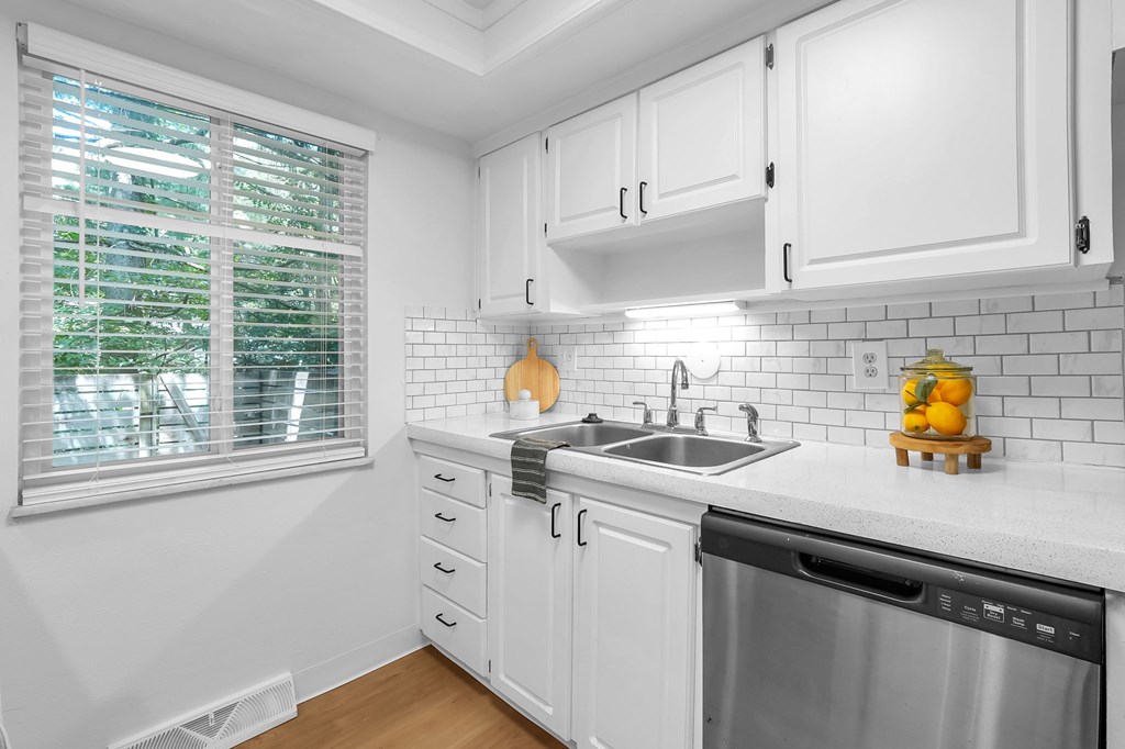 A kitchen with white cabinets and a stainless steel dishwasher.