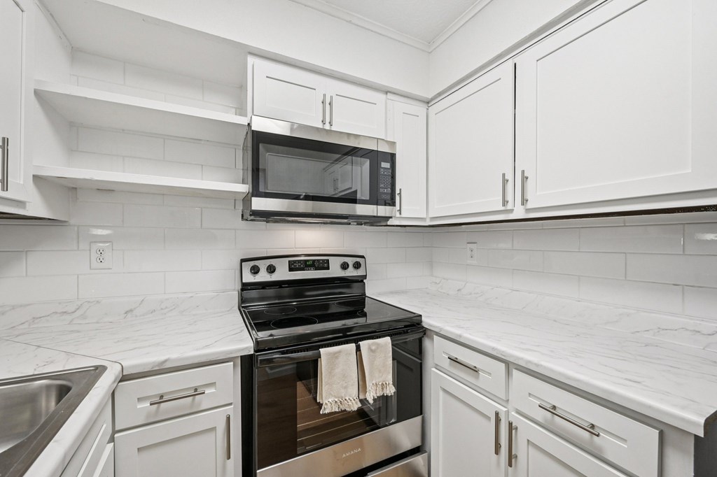 A modern kitchen with a stove top oven and a microwave above it.