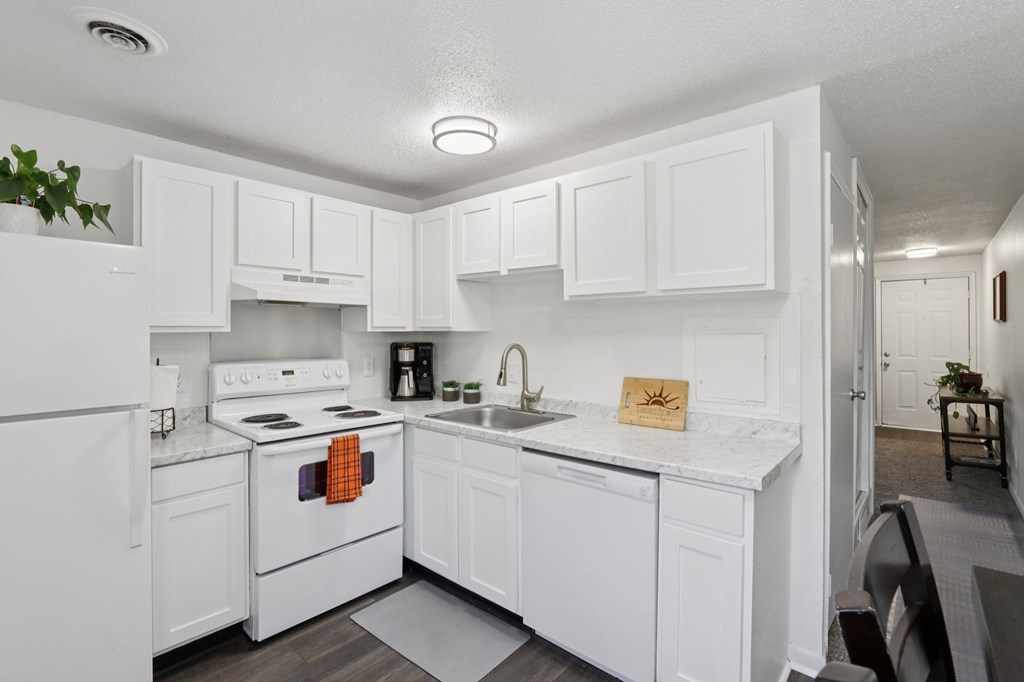 A white kitchen with a stove, oven, and sink.