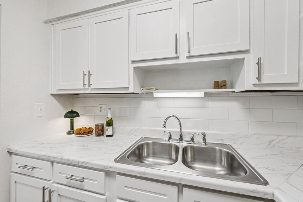A kitchen with a marble countertop and white cabinets.