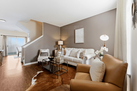 A living room with a brown leather couch and a white sofa.