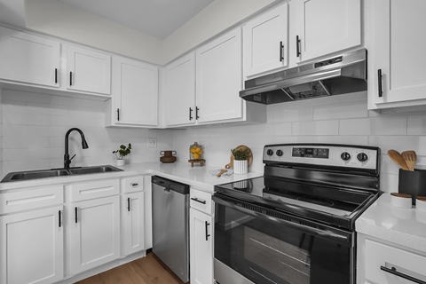 A black and white kitchen with white cabinets and a black stove top oven.