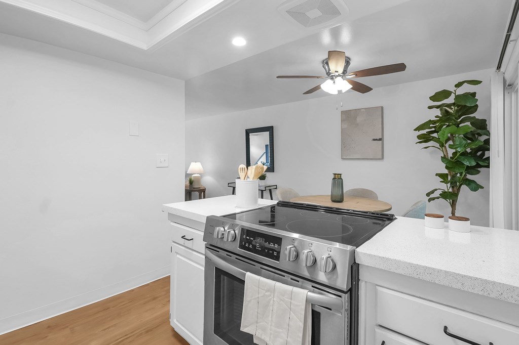 A modern kitchen with a stove top oven and a fan on the ceiling.