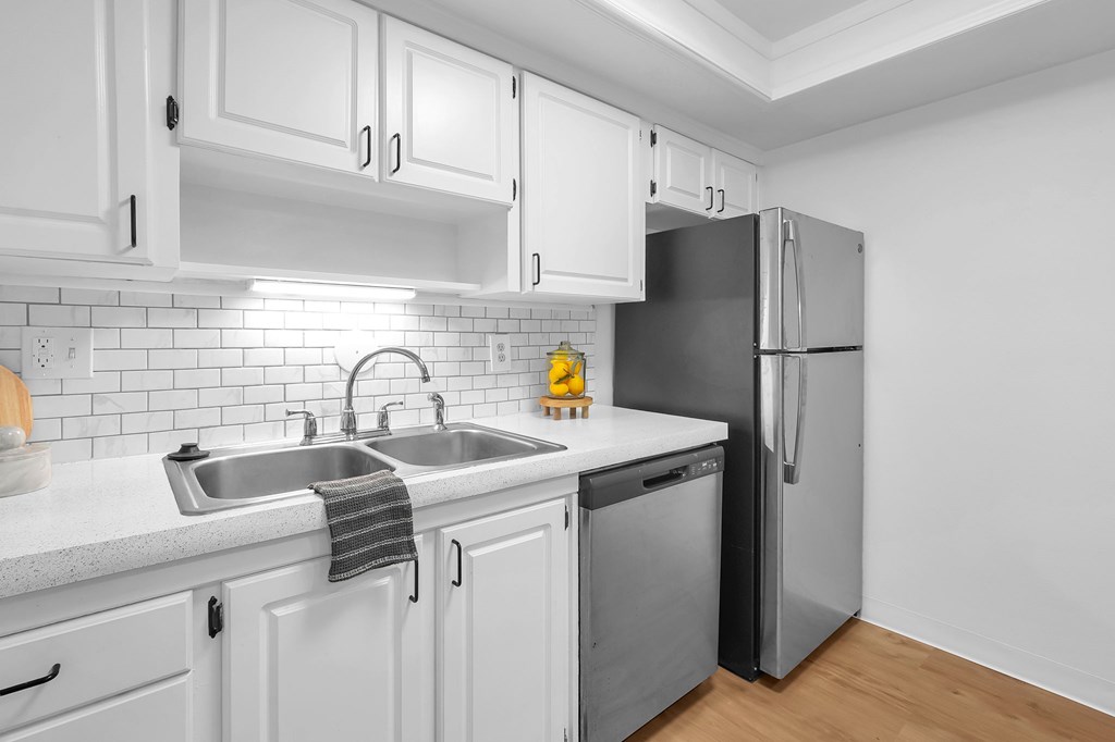 A kitchen with white cabinets and a black fridge.
