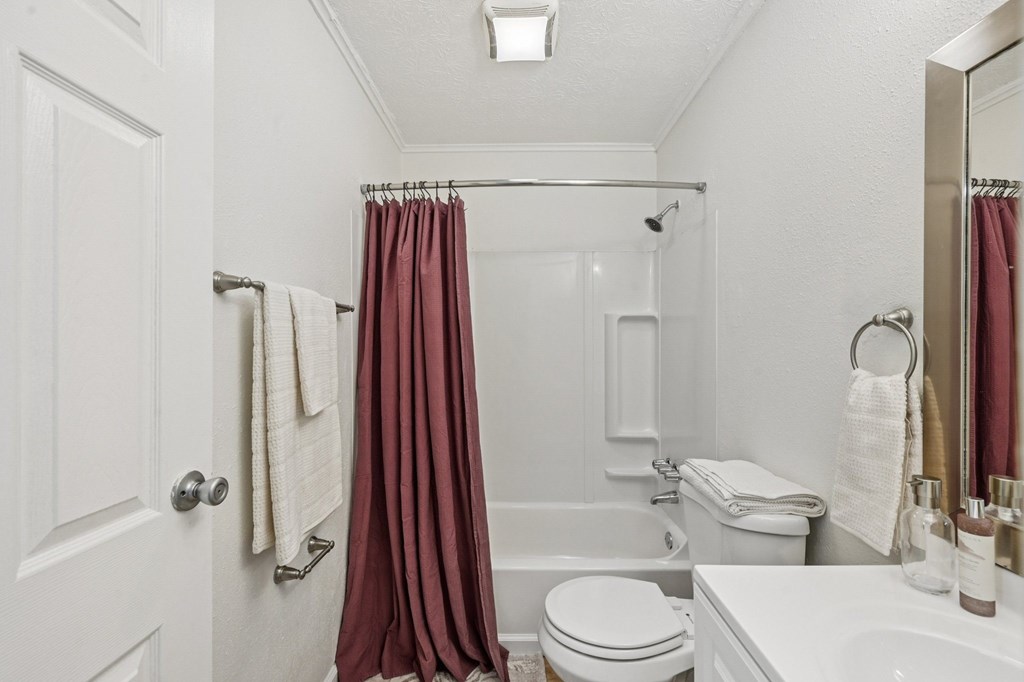 A white bathroom with a toilet, sink, and shower.
