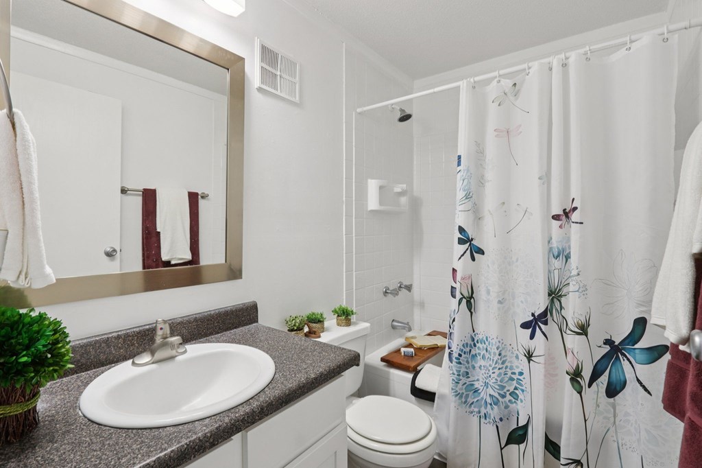 A bathroom with a sink, toilet, and shower curtain.