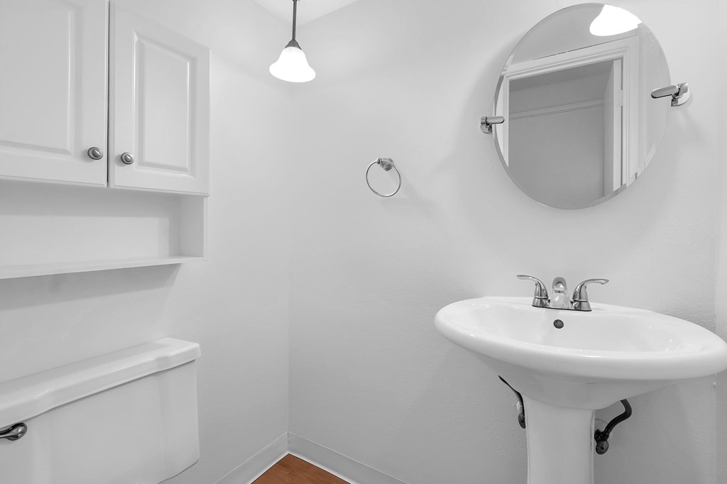 A white bathroom with a sink and mirror.