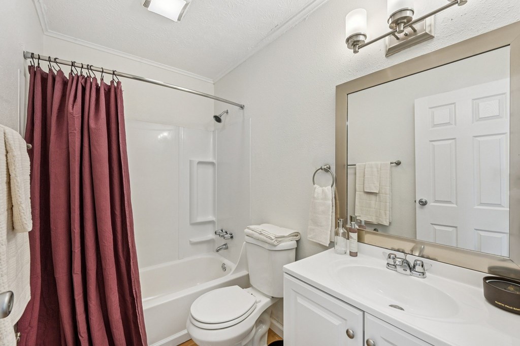 A white bathroom with a toilet, sink, and shower.