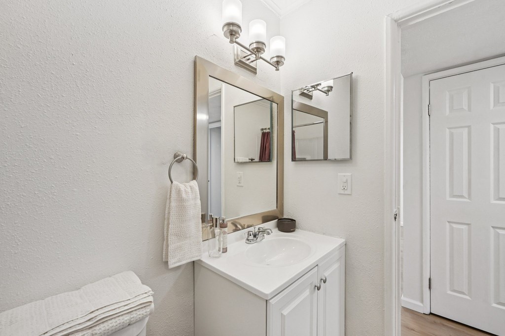 A white bathroom with a sink, mirror, and towel.