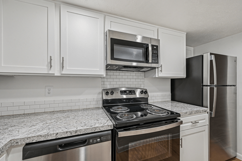 A kitchen with a black stove top oven and a black microwave above it.