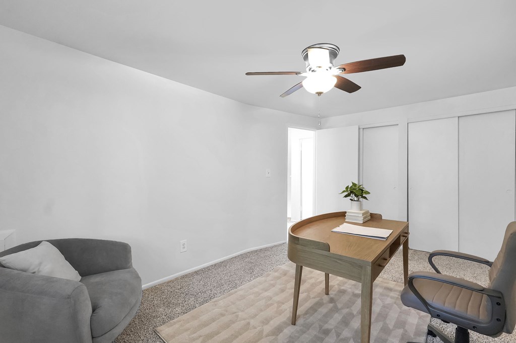 A room with a grey couch, a wooden table with a plant and a book on it, and a grey chair.