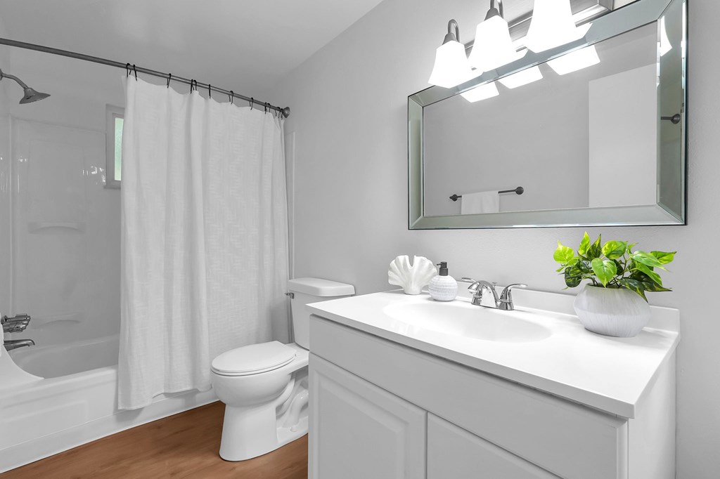 A white bathroom with a toilet, sink, and mirror.