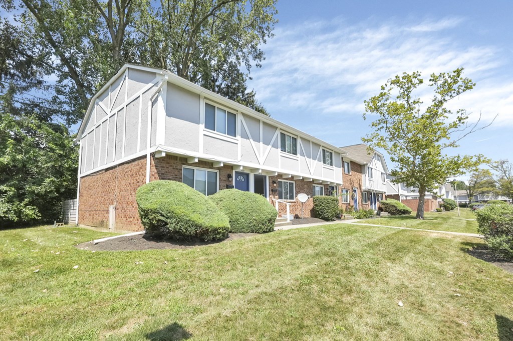 A modern house with a white and brown exterior and a well-maintained lawn.