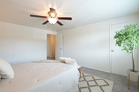 A bedroom with a large bed and a ceiling fan.