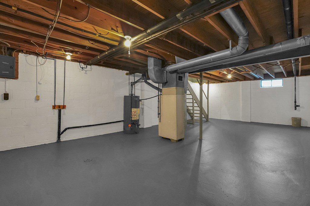 A spacious basement with a concrete floor and a staircase leading to the upper level.