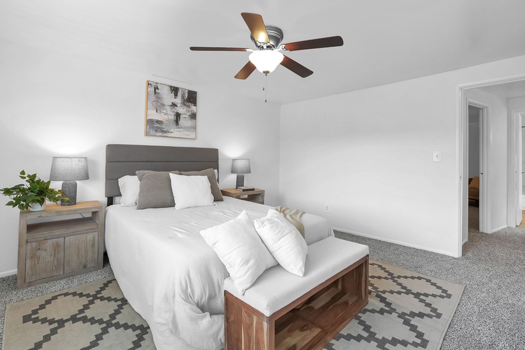 A bedroom with a bed, nightstand, and ceiling fan.
