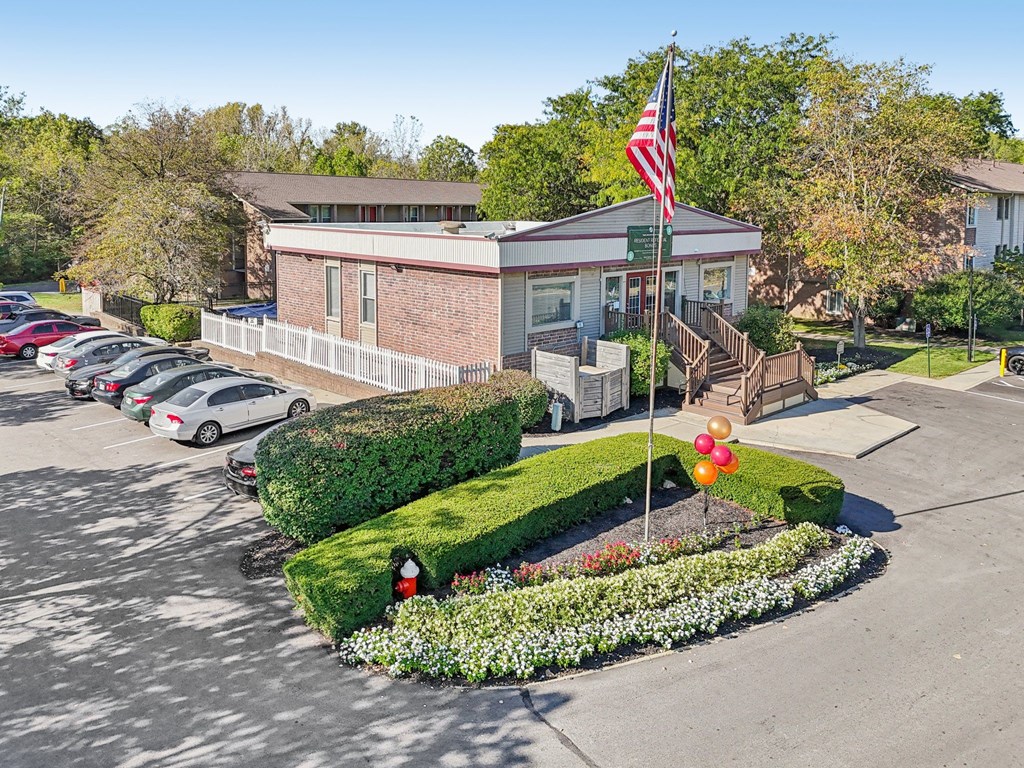 A building with a flag on top and a parking lot in front.