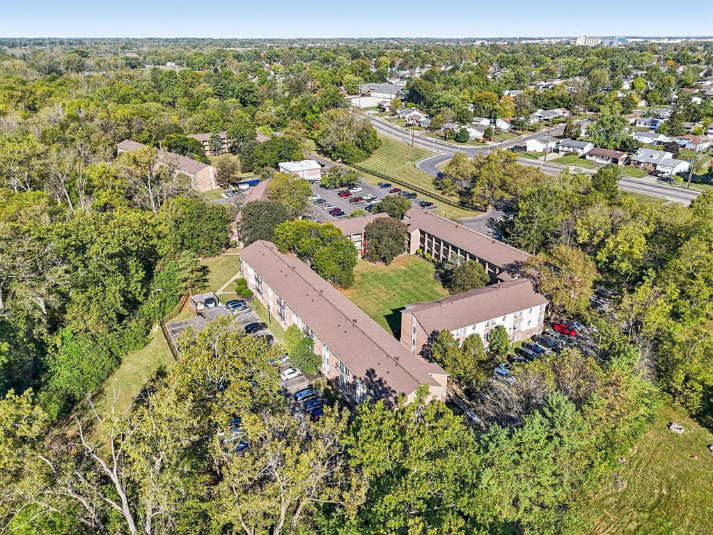 A large building surrounded by trees with cars parked in front.