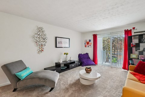 A living room with a grey chair and a white bowl on the carpet.
