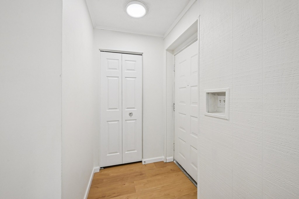 A white door is in a hallway with wood floors.