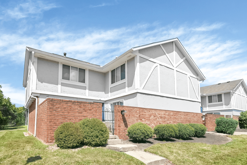 A white house with a brick base and a black door.