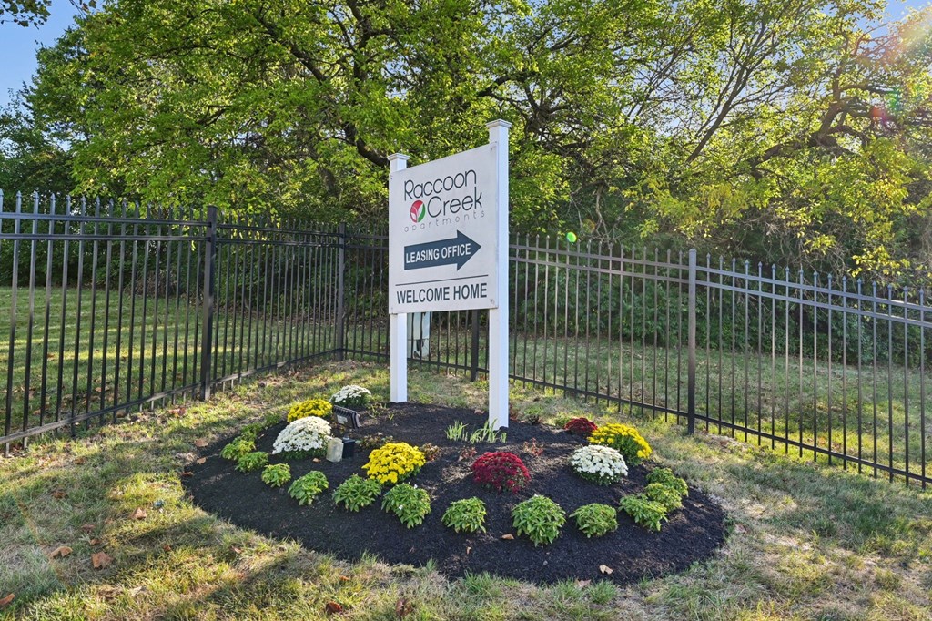 A sign for a place called "Pacoon Creek" stands in a flowerbed.