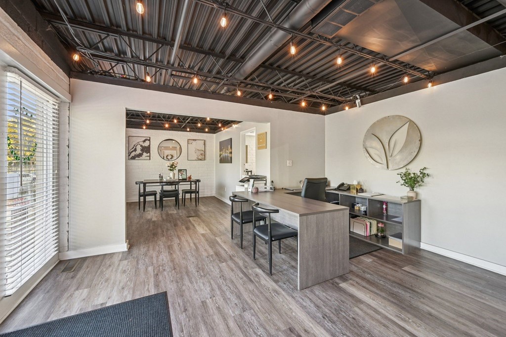A room with a desk and chairs with a leaf design on the wall.