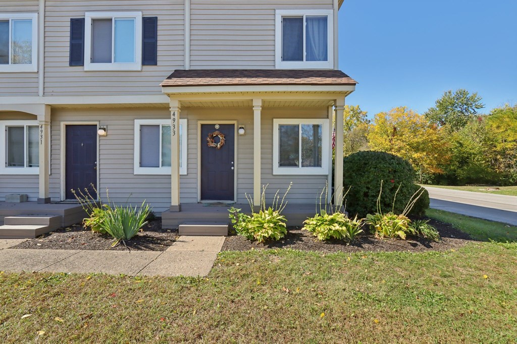 A grey house with a brown door and a wreath on it.