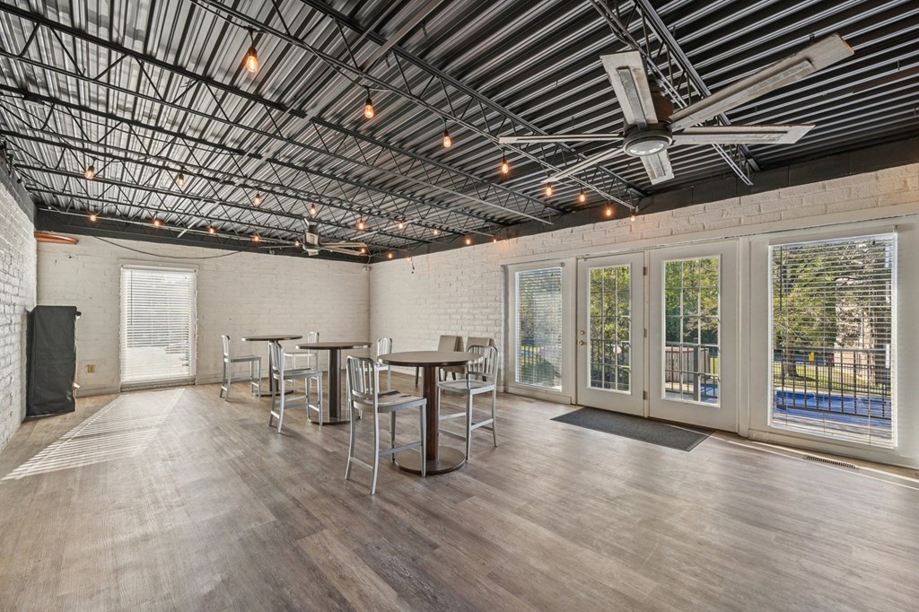 A room with a long table and chairs, a fan, and a window with a view of a pool.