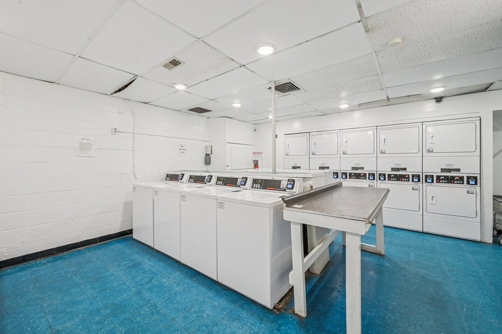 A clean, white room with a blue floor and a table in the middle.