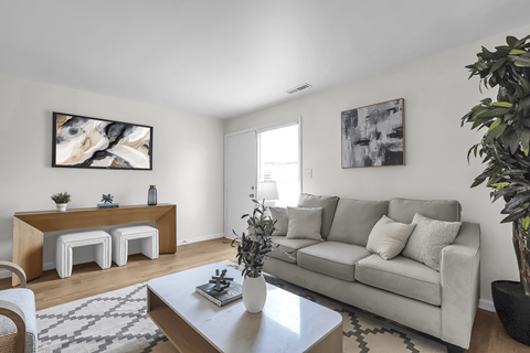 A living room with a grey couch, a white coffee table, and a painting on the wall.