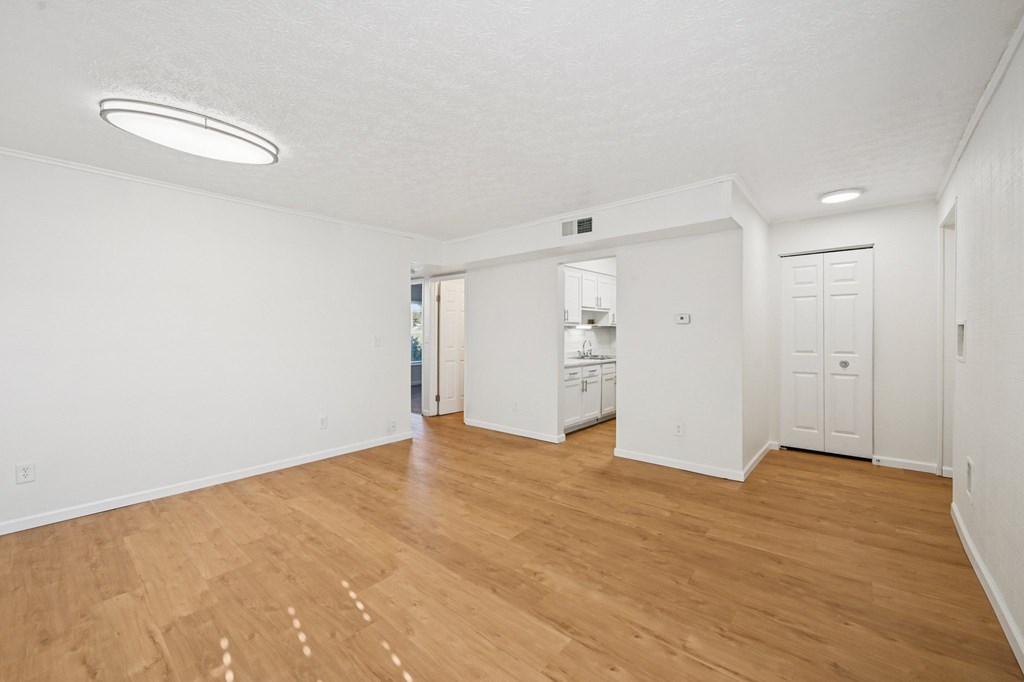 A large empty room with wooden flooring and white walls.